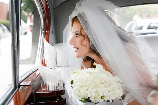 photo by New York based wedding photographer Merri Cry - beautiful bride gazing out the car window - holding a bouquet of white roses